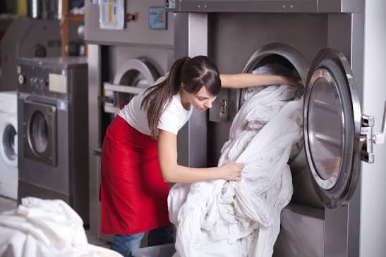 Nhân viên xử lý chăn drap gối bằng máy giặt công nghiệp